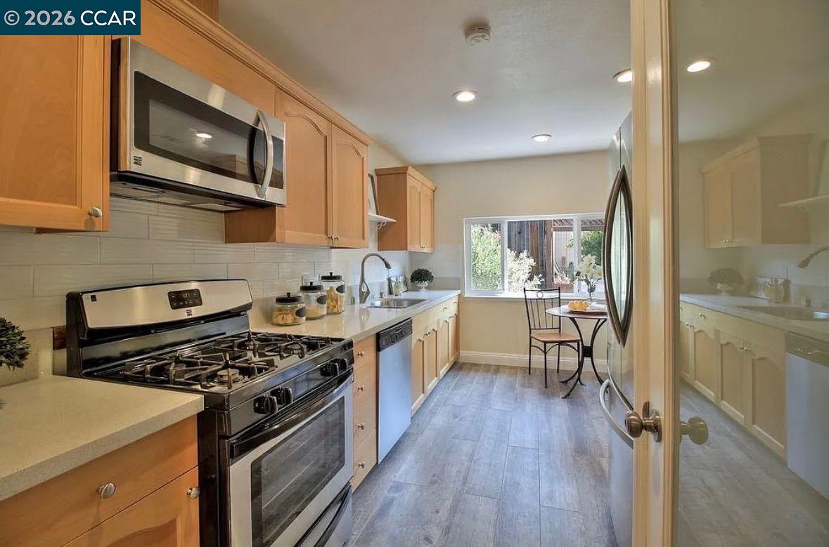 143 Pulido Road Danville, CA 94526 - Photo 19 of 27 a kitchen with stainless steel appliances a stove a sink dishwasher a refrigerator white cabinets and wooden floor next to a window