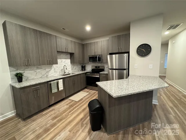 a kitchen with a stove a refrigerator a sink and dishwasher with wooden floor