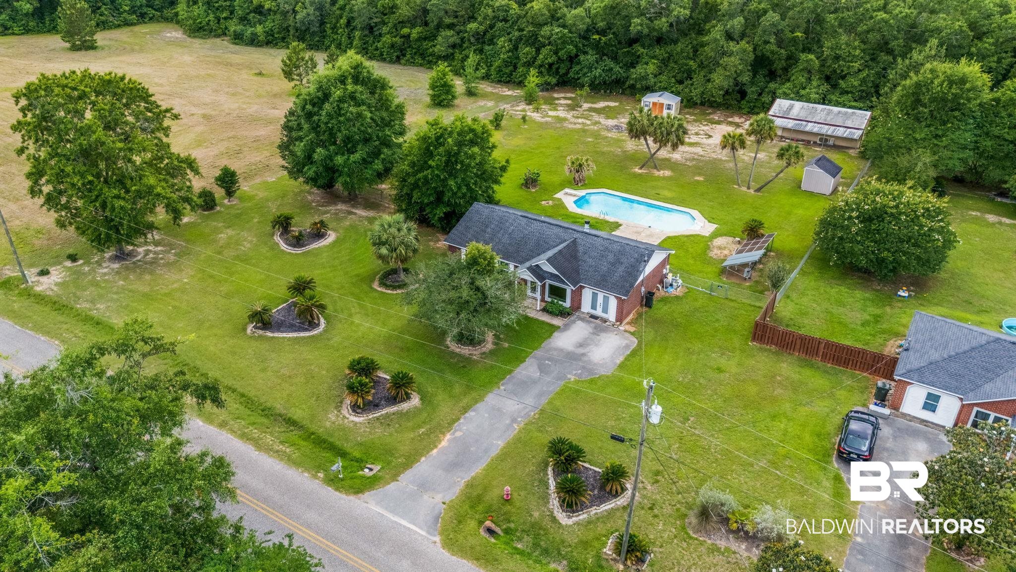 15096 Highland Circle Foley, AL 36535 - Photo 45 of 52 Spacious property featuring a single-story residence, an inground swimming pool, a drive with ample parking, mature trees, and a fenced area