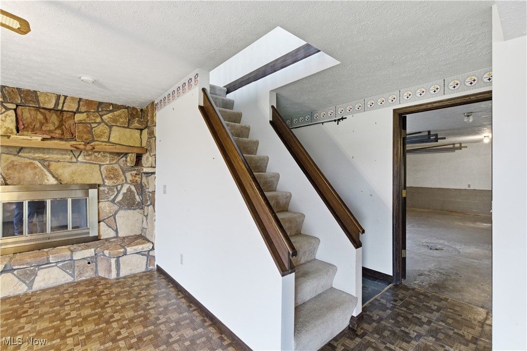 54846 Seneca Lake Road Quaker City, OH 43773 - Photo 8 of 42 Stairway with a textured ceiling and a fireplace