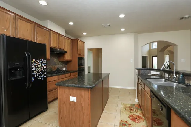 a kitchen with stainless steel appliances granite countertop a sink a stove and a refrigerator