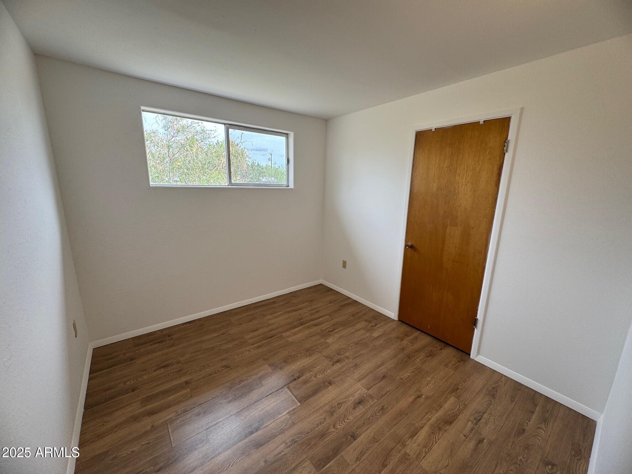 504 Alegre Place Bisbee, AZ 85603 - Photo 13 of 28 a view of an empty room with wooden floor and a window