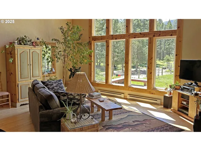 a living room with furniture a flat screen tv and floor to ceiling window