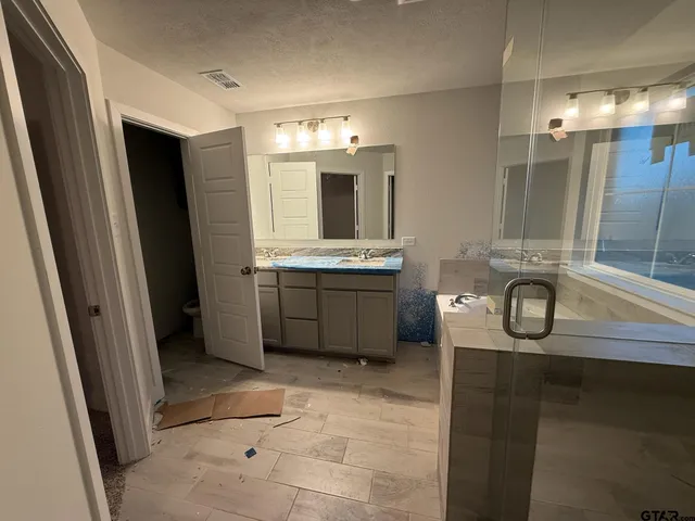 a bathroom with a granite countertop sink a mirror and a shower