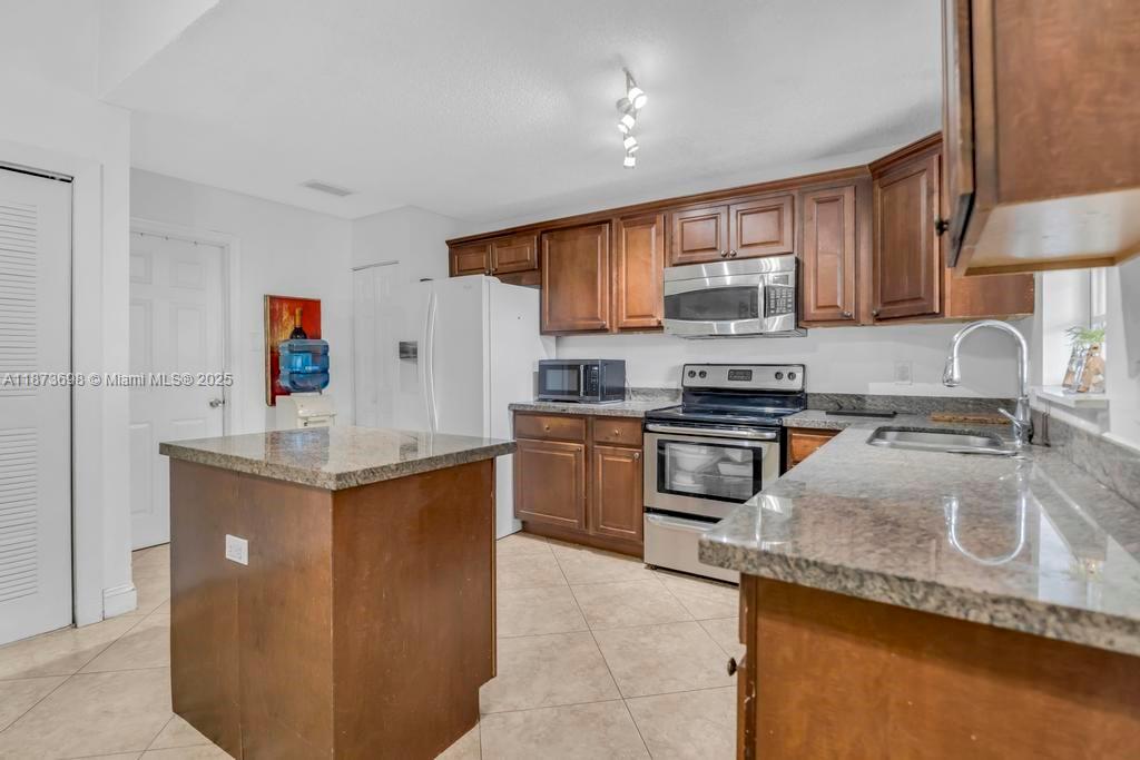 26023 Southwest 133rd Place Homestead, FL 33032 - Photo 12 of 39 a kitchen with a sink a stove and cabinets