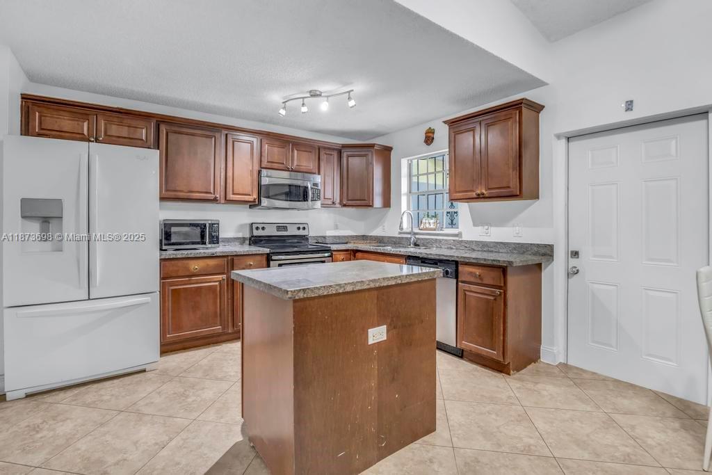 26023 Southwest 133rd Place Homestead, FL 33032 - Photo 13 of 39 a kitchen with stainless steel appliances granite countertop a stove top oven a sink and dishwasher