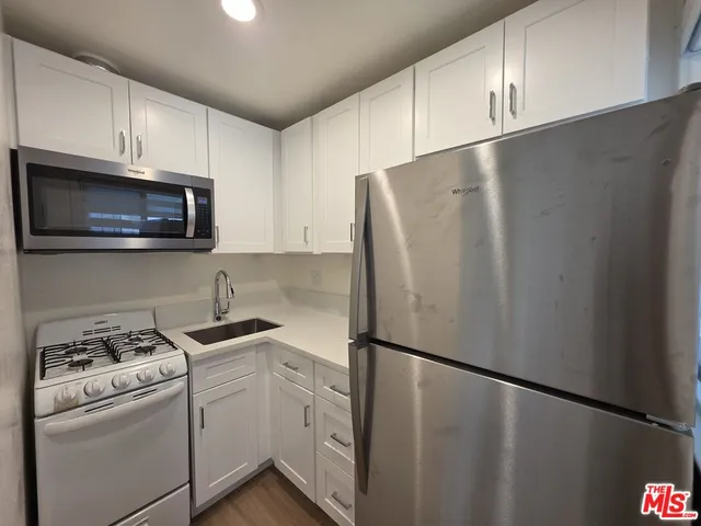 a kitchen with stainless steel appliances white cabinets white stove a refrigerator and a sink