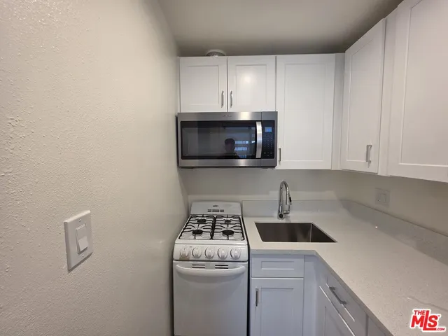 a kitchen with a sink a stove and cabinets