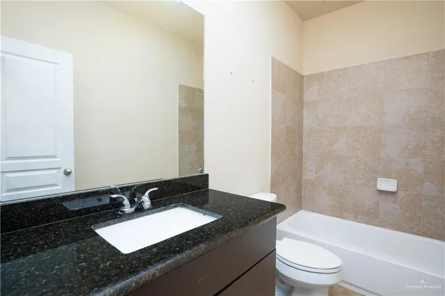 a bathroom with a granite countertop sink mirror vanity and toilet