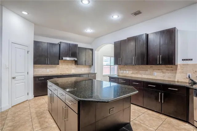 a kitchen with kitchen island granite countertop a sink and refrigerator