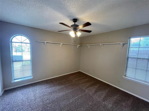 en empty room with windows and fan