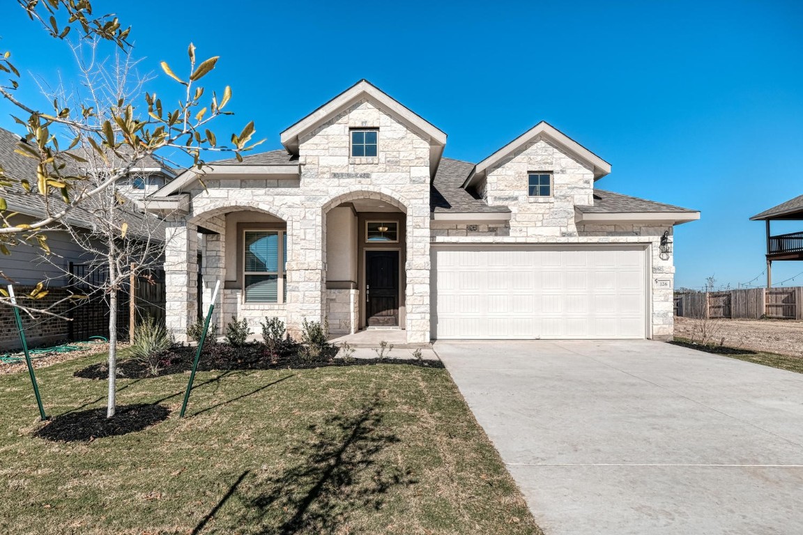 The front of the home is inviting, with stone siding and a driveway that leads to a  two car garage that allows for plenty of parking.