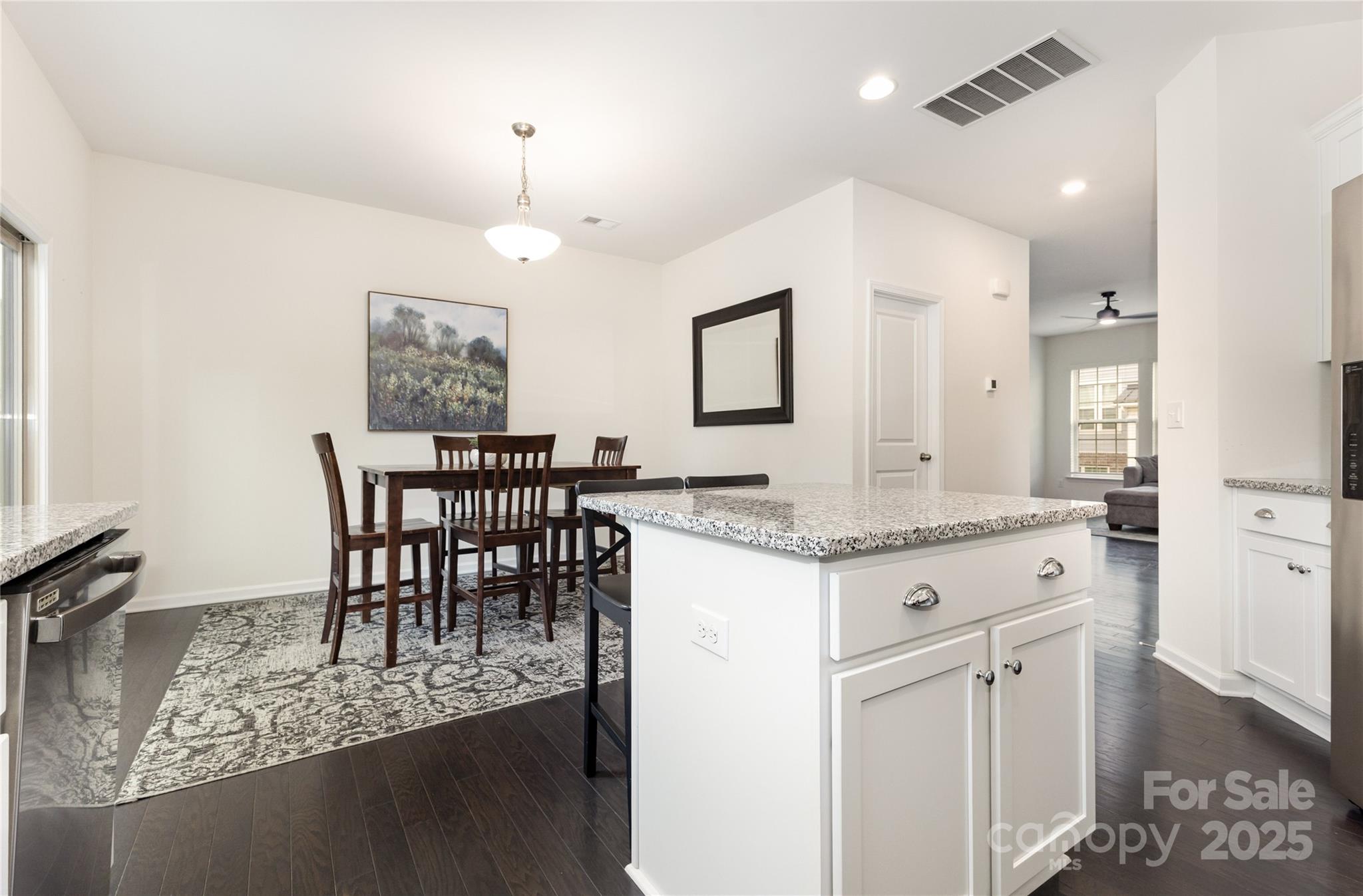 717 Swift Run Tega Cay, SC 29708 - Photo 6 of 39 a kitchen with kitchen island granite countertop a table chairs sink and cabinets
