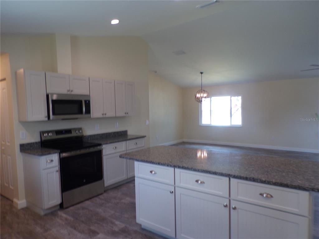 3112 Pinetree Street Port Charlotte, FL 33952 - Photo 29 of 35 a kitchen with granite countertop white cabinets appliances a sink and a window