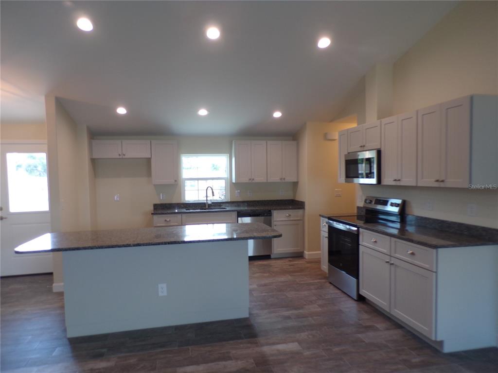 3112 Pinetree Street Port Charlotte, FL 33952 - Photo 6 of 35 a large kitchen with granite countertop a stove top oven a sink a counter space and cabinets