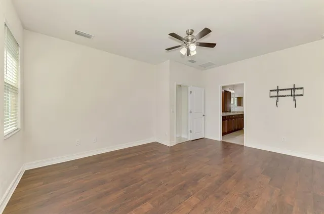 a view of empty room with wooden floor and ceiling fan