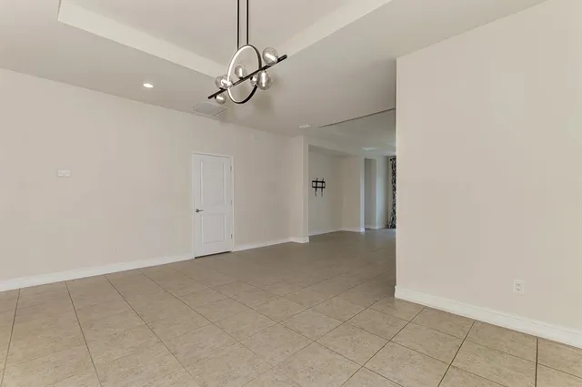 a view of an empty room with a chandelier fan