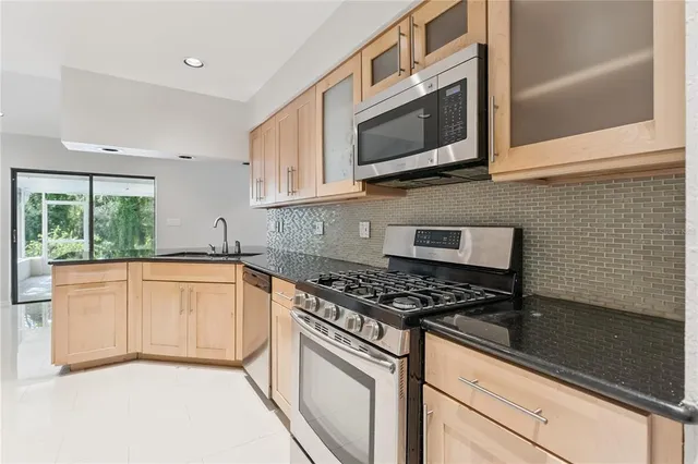 a kitchen with stainless steel appliances granite countertop white cabinets granite counter tops and a window
