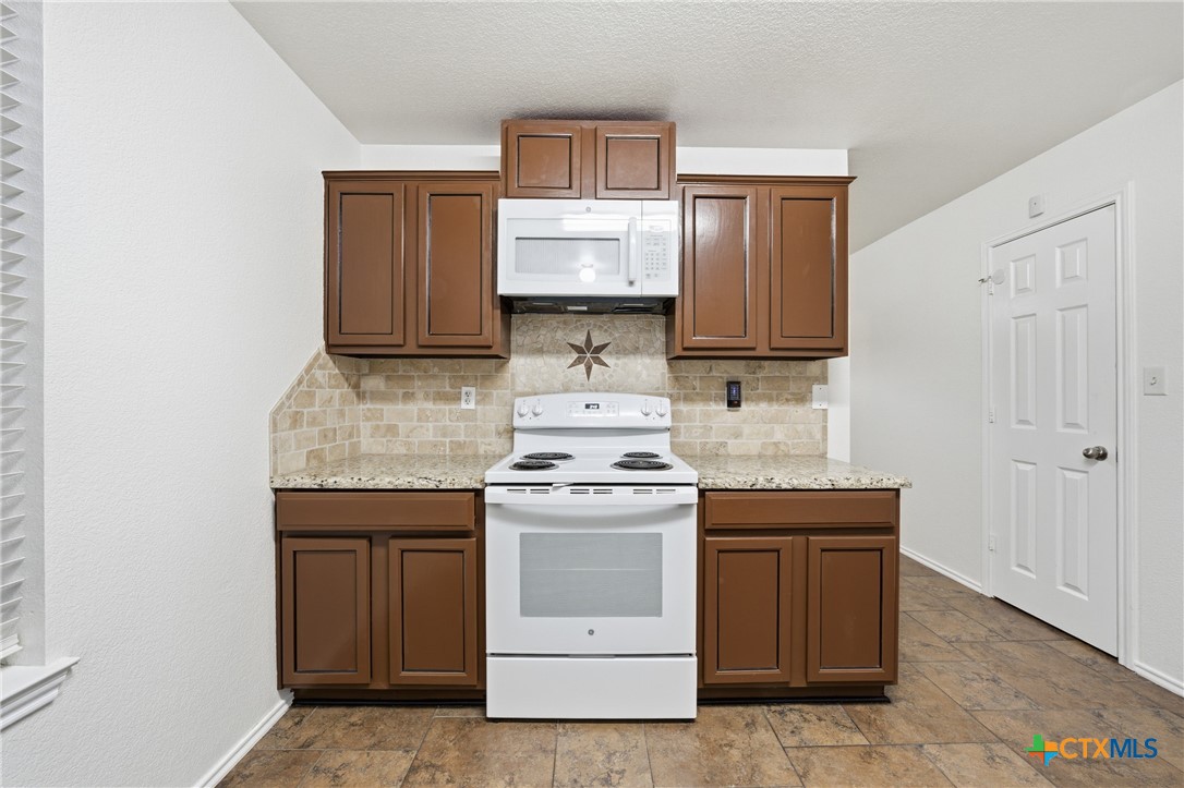 6525 Brooks Drive Temple, TX 76502 - Photo 17 of 37 a kitchen with granite countertop wood cabinets and white appliances