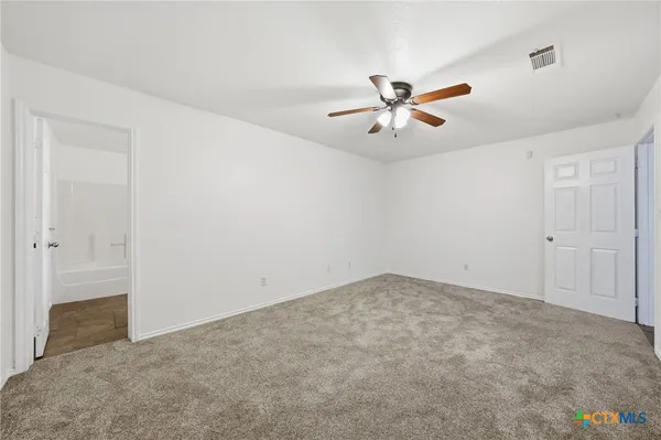 an empty room with closet and a ceiling fan