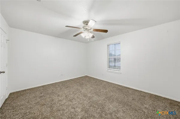 a view of an empty room with a ceiling fan and window