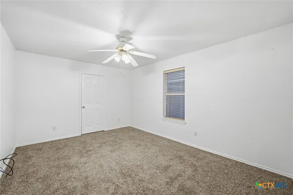 an empty room with a chandelier fan and windows