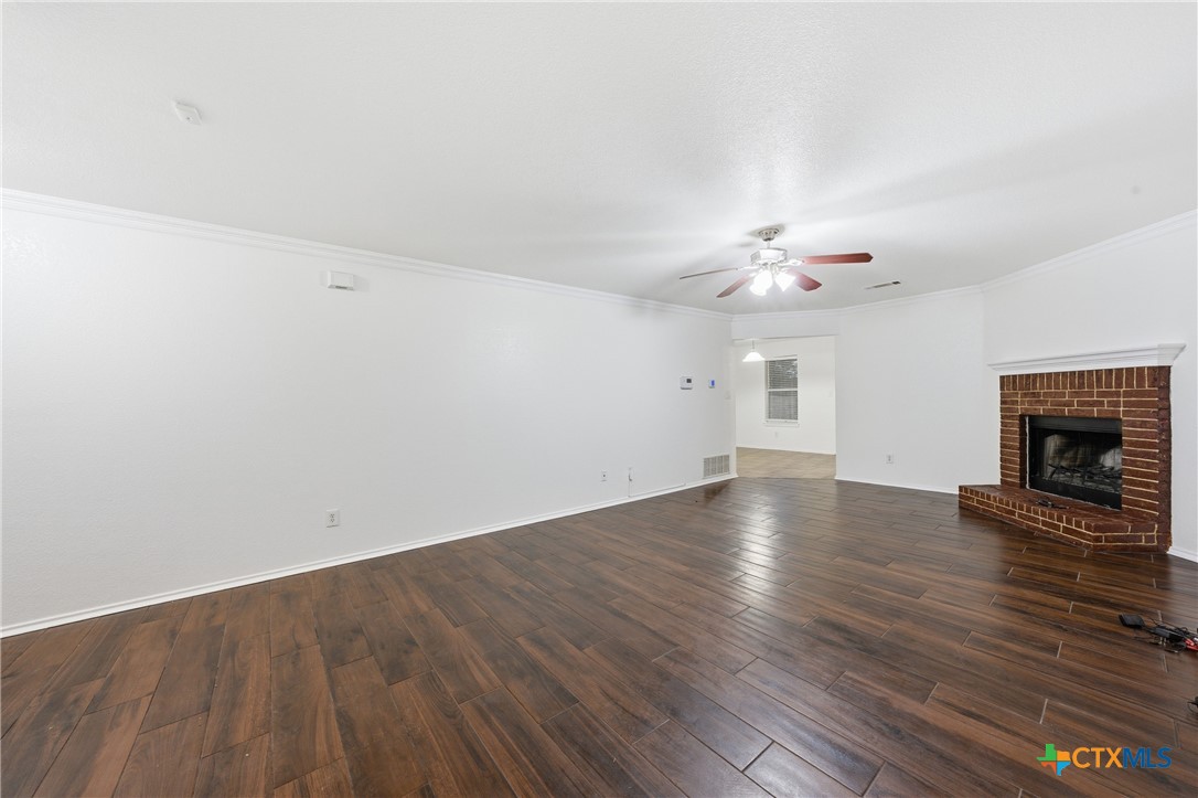6525 Brooks Drive Temple, TX 76502 - Photo 8 of 37 an empty room with wooden floor fireplace and chandelier fan