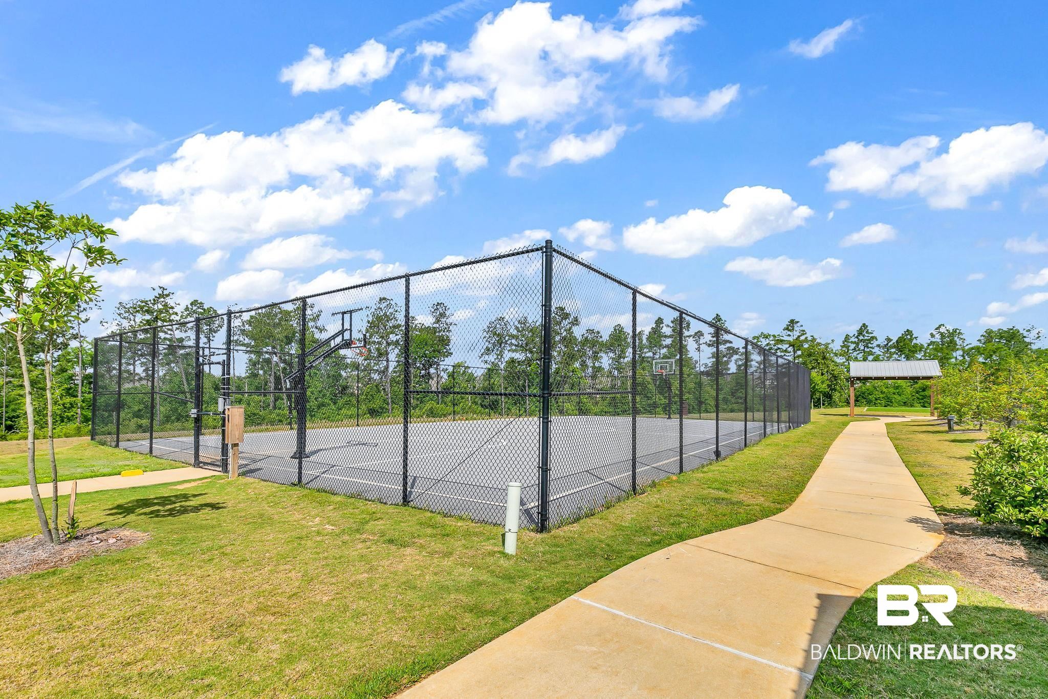 13233 Ibis Boulevard Daphne, AL 36527 - Photo 87 of 100 Fenced basketball court featuring a gray playing surface, black chain-link fencing, and multiple hoops
