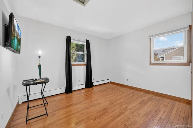 a view of an empty room with window and wooden floor