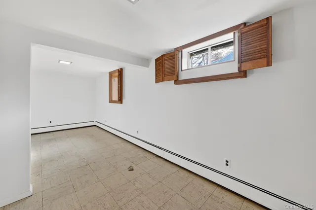 an empty room with windows and refrigerator