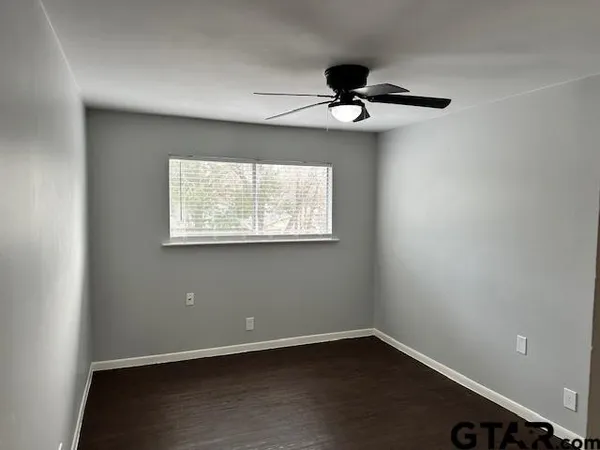 an empty room with a window and ceiling fan