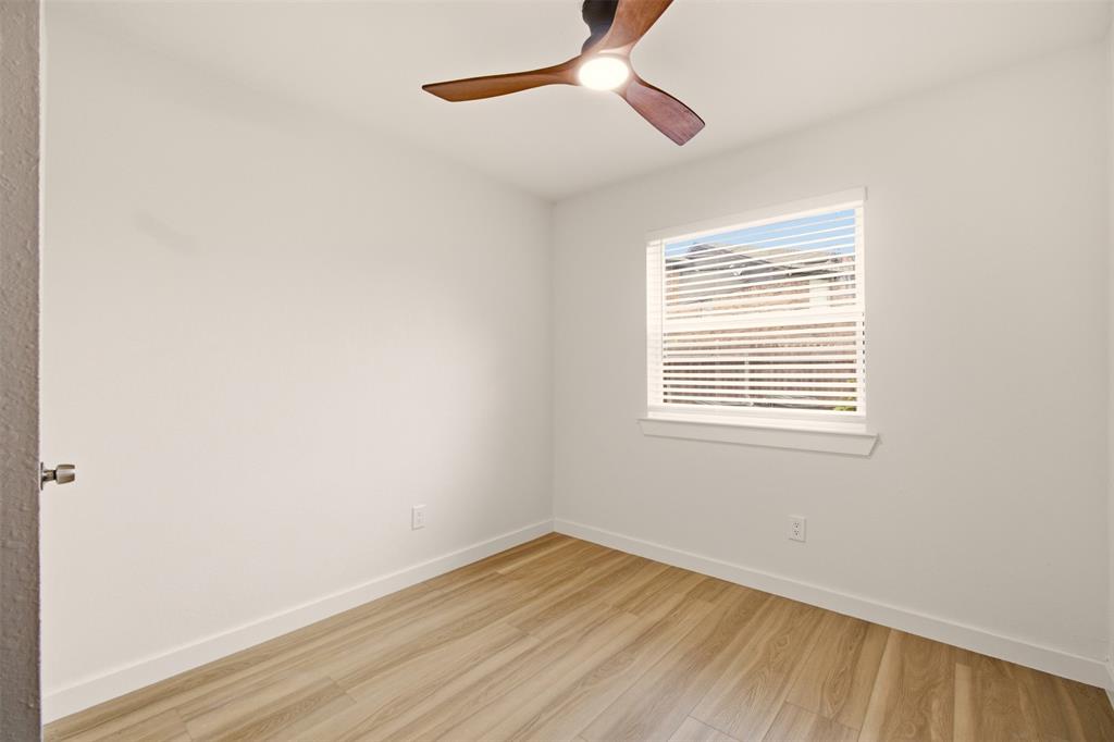 908 Isbell Road, Unit A Fort Worth, TX 76114 - Photo 24 of 28 Bright room featuring a ceiling fan with integrated lighting, a single window with blinds, wood-finish flooring, and white baseboards
