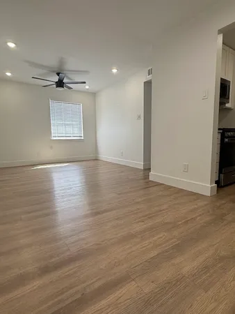 an empty room with wooden floor a ceiling fan and windows