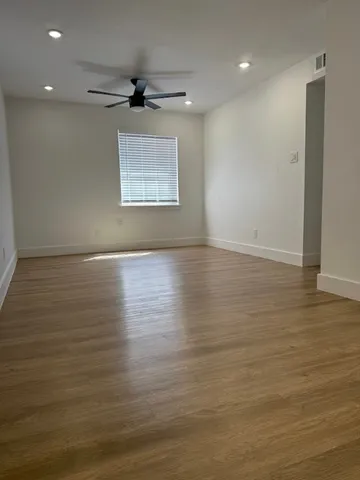 an empty room with wooden floor and a ceiling fan