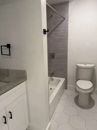 a bathroom with a granite countertop sink a toilet and bathtub