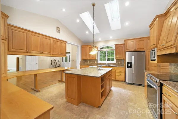a kitchen with stainless steel appliances granite countertop a sink a stove and a refrigerator