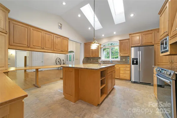 a kitchen with stainless steel appliances granite countertop a refrigerator a sink and a stove