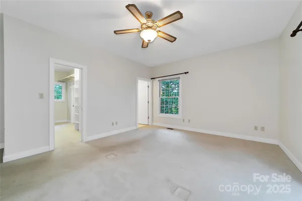 an empty room with closet and a ceiling fan