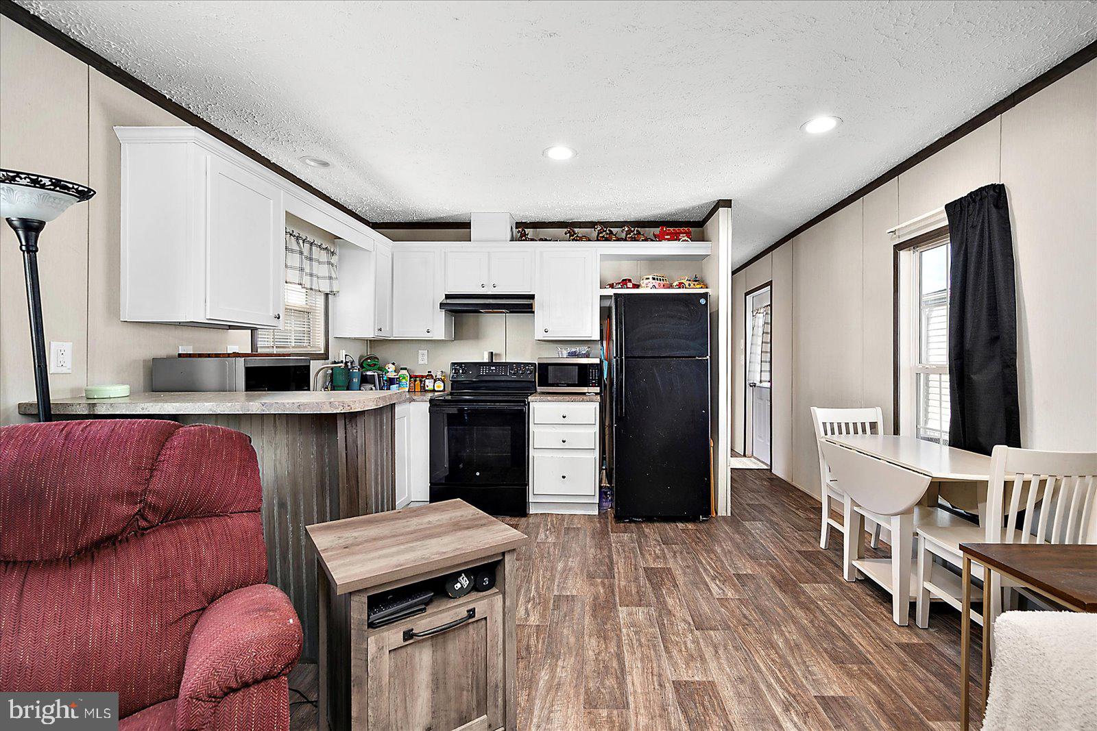 12346 Old Bridge Road, Unit 152 Ocean City, MD 21842 - Photo 12 of 55 a kitchen with stainless steel appliances granite countertop a refrigerator a sink dishwasher a stove and a dining table with wooden floor