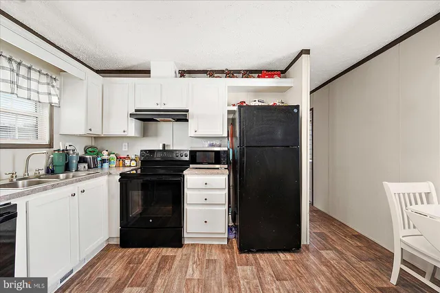 a kitchen with stainless steel appliances a refrigerator cabinets and wooden floor