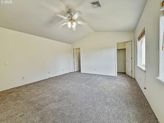 a view of an empty room with a chandelier fan