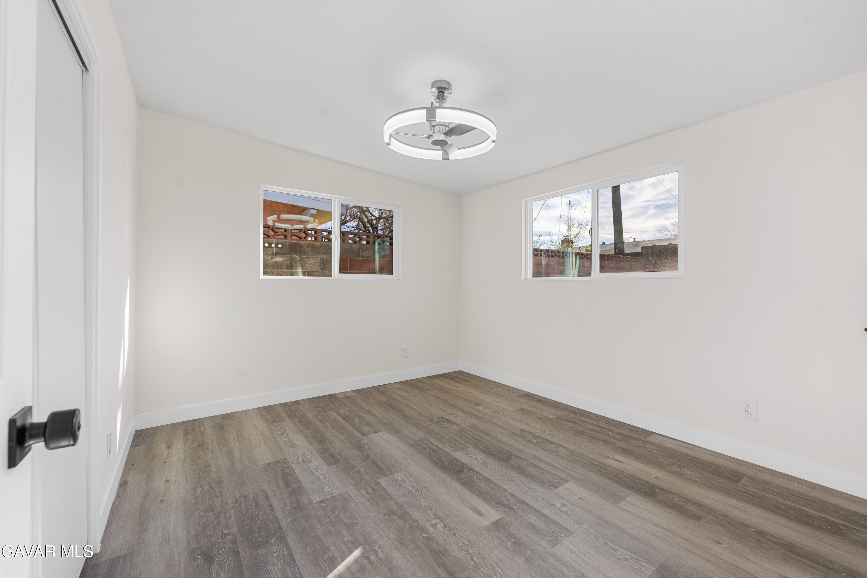44745 3rd Street East Lancaster, CA 93535 - Photo 8 of 30 an empty room with wooden floor ceiling fan and windows
