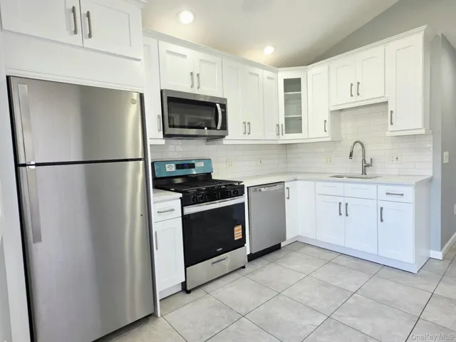 a kitchen with white cabinets stainless steel appliances and a sink