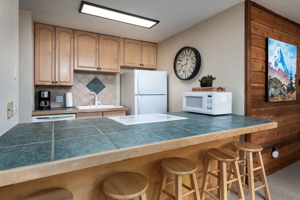 500 4 O Clock Road, Unit A22 Breckenridge, CO 80424 - Photo 15 of 16 a kitchen with kitchen island granite countertop a wooden cabinets and a clock on wall
