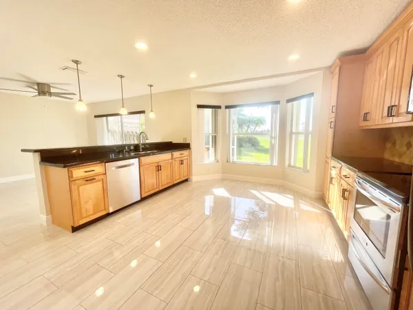 a large kitchen with granite countertop a stove a sink and white cabinets with wooden floor