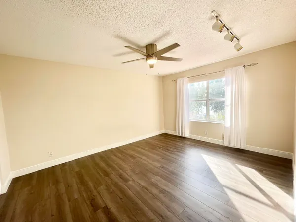 an empty room with wooden floor fan and windows