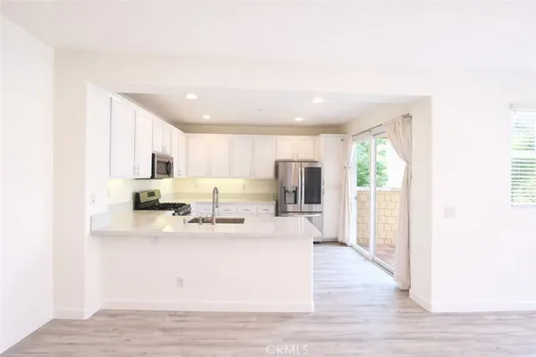 a view of kitchen with stainless steel appliances granite countertop refrigerator stove top oven and cabinets