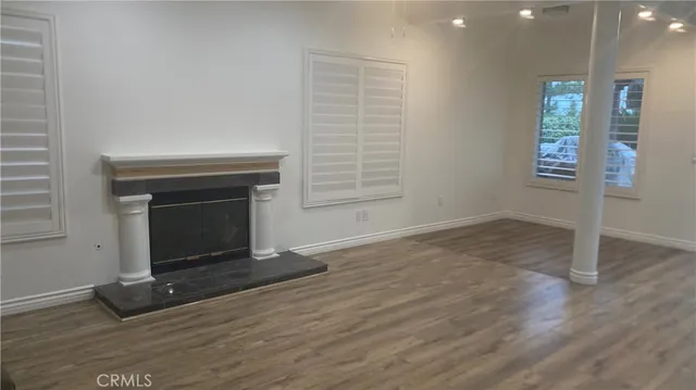 an empty room with wooden floor a fireplace and windows