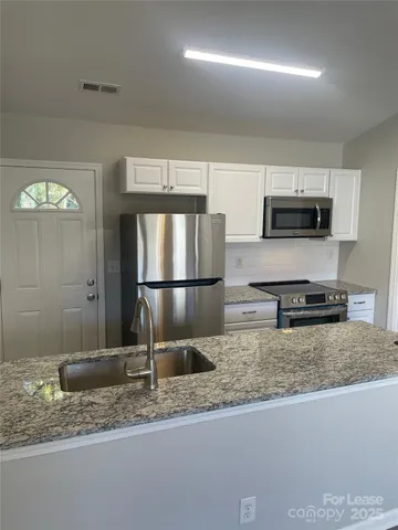 a kitchen with granite countertop a refrigerator and a sink