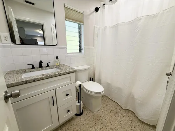 a bathroom with a granite countertop toilet sink and mirror